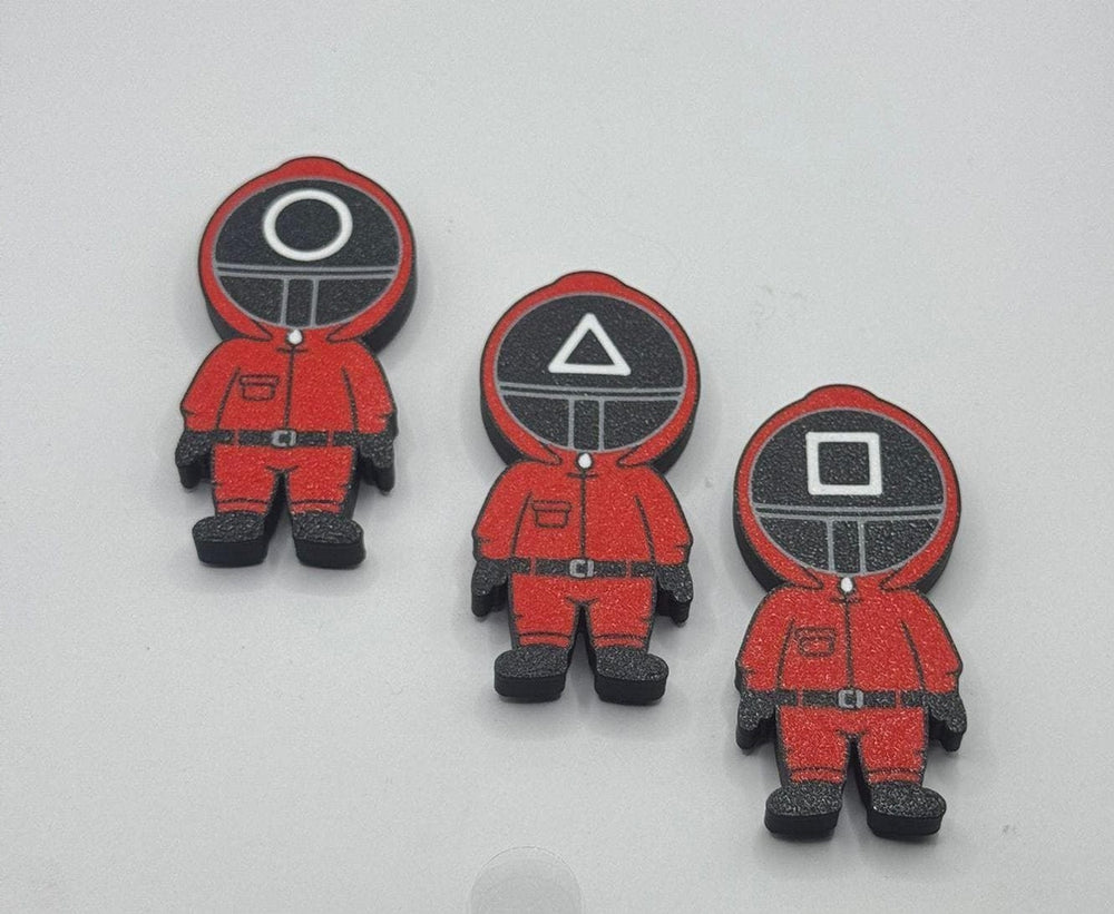 Three red character figurines with different symbol designs on their heads against a white background