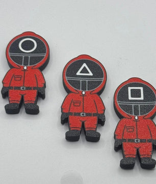 Three red character figurines with different symbol designs on their heads against a white background