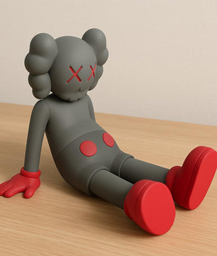 Gray and red toy figure with a minimalistic design on a wooden surface.